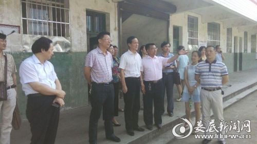 （刘宏业等领导在科头中学教学楼一楼走廊上听取罗渊恒校长情况介绍）