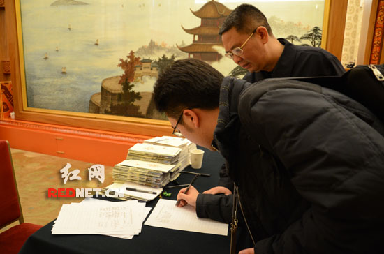 根据大会安排，今天的全体会议向中外媒体开放，图为一名记者在入口处签到。