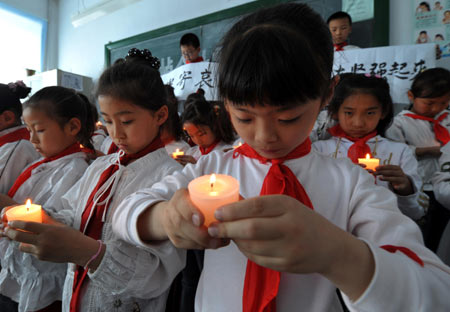 Pupils holding candles mourn during a silent tribute in Harbin, capital of northeast China's Heilongjiang Province, May 19, 2008.