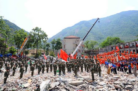Rescuers mourn during a silent tribute on the debris of a collapsed middle school building in Beichuan County, southwest China's Sichuan Province, May 19, 2008. China began on May 19 a three-day mourning for the victims of the 8.0-magnitude quake hitting southwest and northwest China on May 12. (Xinhua/Li Tao)