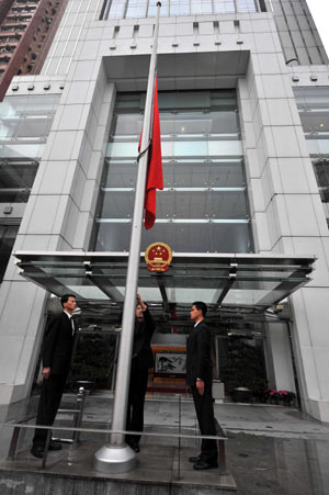 Staffers of the Liaison Office of the Central People's Government in the Hong Kong Special Administrative Region watch as China's national flag flies at half-mast in Hong Kong, south China, May 19, 2008. China on Monday begins a three-day national mourning for the tens of thousands of people killed in a powerful earthquake which struck southwest China's Sichuan province on May 12.