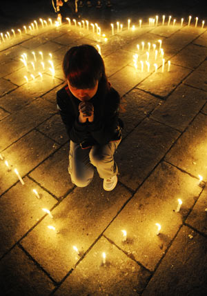 A girl mourns in heart-shaped candles at a memorial ceremony in Changchun, capital of northeast China's Jilin Province, May 19, 2008. China began on Monday a three-day mourning for the victims of the 8.0-magnitude quake on Richter scale hitting southwest and northwest China on May 12.