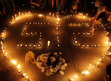 People mourn around candles at a memorial ceremony in Chengdu, capital of southwest China's Sichuan Province, May 19, 2008. China began on Monday a three-day mourning for the victims of the 8.0-magnitude quake on Richter scale hitting southwest and northwest China on May 12.