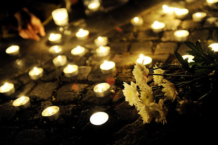 People lay candles and flowers at the square in front of the assembly building during a candlelight memorial activity in Berlin, capital of Germany, May 19, 2008. People held a candlelight memorial here Monday to mourn thousands of victims killed in the 8.0-magnitude earthquake on Richter scale which hit southwest and northwest China's regions.