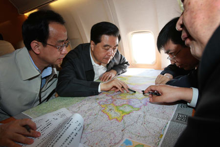 Chinese President Hu Jintao (2nd L) discusses with officials the quake relief work during his flight to the disaster area in southwest China's Sichuan Province May 16, 2008. President Hu flew to quake-hit southwestern Sichuan Province Friday morning to console the victims and inspect the rescue and relief work.
