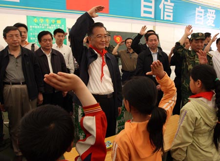 Chinese Premier Wen Jiabao (C) salutes with the students to pay tribute to the quake victims during his visit to the makeshift tent school at Jiuzhou Stadium in Mianyang City, southwest China's Sichuan Province, May 23, 2008. Wen Jiabao went to the temporary schoolhouse of Beichuan Middle School and the makeshift tent school established at Jiuzhou Stadium in Mianyang on Friday to visit teachers and students who survived the May 12 earthquake.