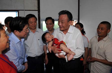 Wu Bangguo, chairman of the Standing Committee of the National People's Congress and a member of the Standing Committee of the Political Bureau of the Communist Party of China (CPC) Central Committee, holds a 8-month-old baby in his arms during his visit to a resettlement area in Dujiangyan, one of the earthquake-hit cities in southwest China's Sichuan Province, May 27, 2008. Wu arrived in Wenchuan County and Dujiangyan city on Tuesday to direct disaster relief work in the quake-ravaged areas.