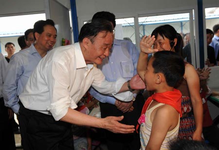  Wu Bangguo, chairman of the Standing Committee of the National People's Congress and a member of the Standing Committee of the Political Bureau of the Communist Party of China (CPC) Central Committee, talks with a student while visiting a temporary school at a resettlement area in Dujiangyan city, southwest China's Sichuan Province, May 27, 2008. Wu arrived in Wenchuan County and Dujiangyan city on Tuesday to direct disaster relief work in the quake-ravaged areas.
