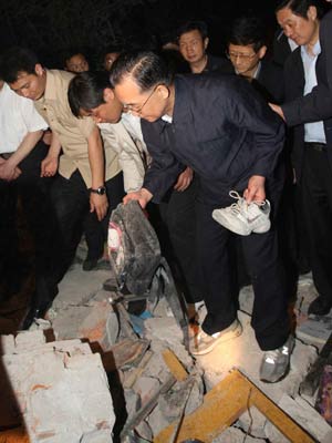 Chinese Pemier Wen Jiabao (C) picks up a shoe and a schoolbag at a ruined school in Dujiangyan city of southwest China's Sichuan Province May 12, 2008. Premier Wen flew into southwest China's Sichuan Province on Monday. 