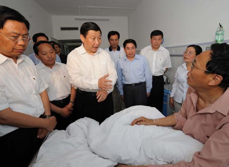 Chinese Vice President Xi Jinping (C), also a member of the Standing Committee of the Communist Party of China (CPC) Central Committee Political Bureau, talks to an injured relief worker in a local hospital as he visits the quake-affected Hanzhong of northwest China's Shaanxi Province May 19, 2008. 