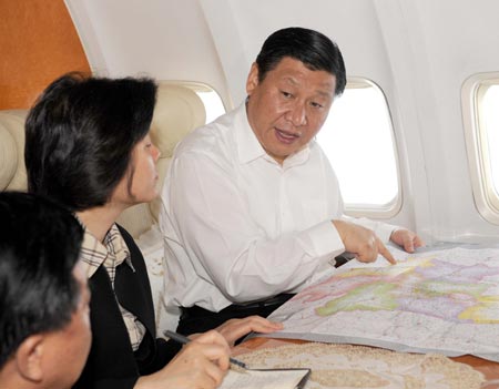 Chinese Vice President Xi Jinping (R), also a member of the Standing Committee of the Communist Party of China (CPC) Central Committee Political Bureau, studies the disaster situation on the plane on his way to the quake-affected northwest China's Shaanxi Province May 19, 2008. 