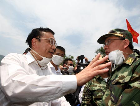 Chinese Vice Premier Li Keqiang (L), also member of the Standing Committee of the Political Bureau of the Communist Party of China (CPC) Central Committee, speaks to a rescuer during his visit to the quake-hit southwest China's Sichuan Province to direct quake relief on May 19, 2008. 