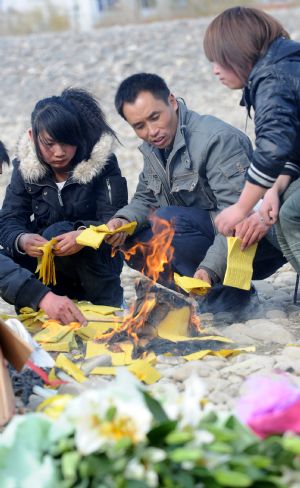 Photo taken on March 14, 2009 shows the manager of the Yishion garment store Tang Qingyan (C) and employees mourn by the Lhasa river the five sales assistants burned to death in an arson attack by the rioters on March 14, 2008, in Lhasa, capital of southwest China's Tibet Autonomous Region. (Xinhua/Soinam Norbu)