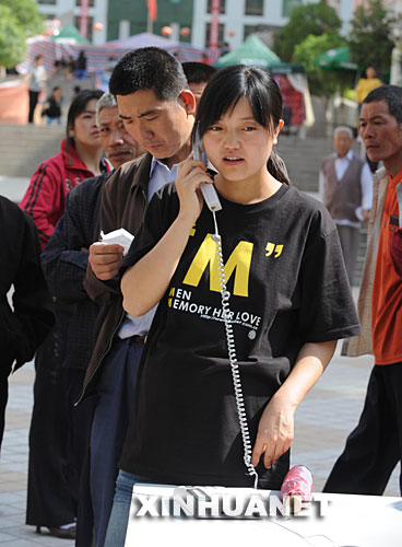 5月14日，甘肃省陇南市文县城区一名女子正在使用“亲情热线”。 5月12日，与四川省接壤的甘肃省文县发生强烈地震后，当地电信部门在城区设置了免费的亲情服务热线，让当地居民与外地的亲友保持联络。