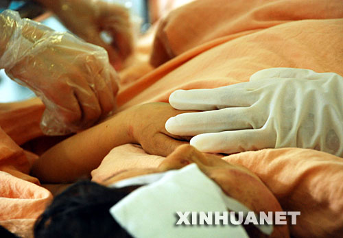 5月15日，成都华西医院的医护人员摸着伤员的手，给他鼓励。 在四川地震灾区，解放军、武警、公安、边防、消防官兵以及民兵、医疗救护人员和志愿者们，不怕危险，不畏疲劳，为抢救每一条宝贵的生命连续奋战。他们是最可爱的人。 新华社发(徐媛媛 摄) 