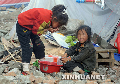 5月18日，在茂县县城一处灾民聚集的生活区，两名小女孩在洗脸。目前，四川省茂县县城已恢复自来水供应，移动和电信信号通讯也基本恢复。