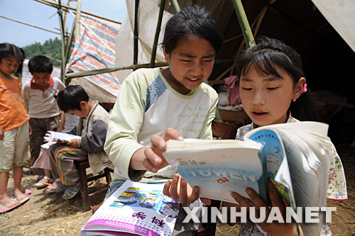 5月18日，青川县蒿溪乡青光村的马金娥（左）、王玉华在临时搭建的帐篷前看书。 四川汶川特大地震灾害发生以来，生活在灾区的孩子们受到了社会各界的极大关注。目前灾区正加紧设立临时课堂，确保孩子们尽快复课，同时组织教师和志愿者科学有效地开展心理辅导和各种集体活动，帮助孩子们尽快走出灾难阴影。